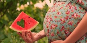 plátek melounu v ruce těhotné ženy